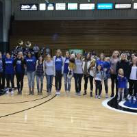 GVSU volleyball alumni and their kids pose for a photo on the volleyball court